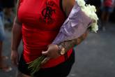 Mulher com flores brancas em enterro de jovem que morreu no incêndio no CT do Flamengo
