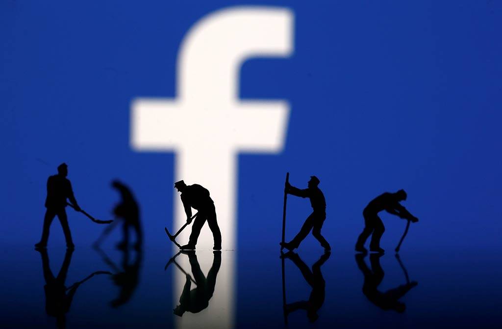 Figurines are seen in front of the Facebook logo in this illustration