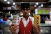 Waiter poses holding beer cans inside a bar in Sao Paulo